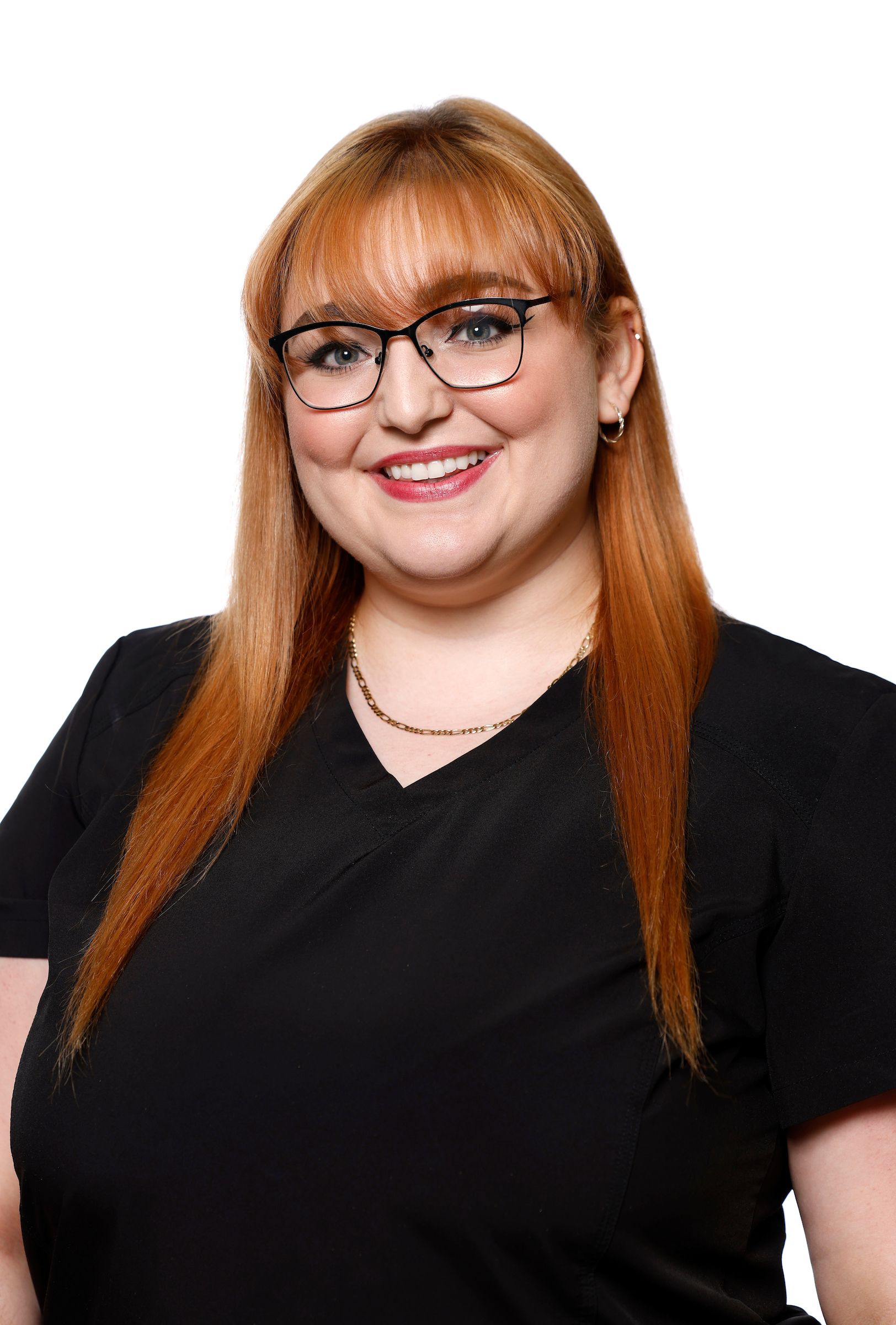 Une femme aux cheveux roux et aux lunettes sourit, vêtue d'un haut noir.