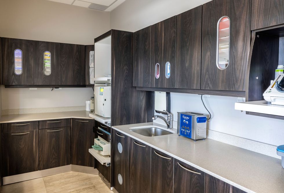 Dark wood cabinets and white countertops in a dental office sterilization area.