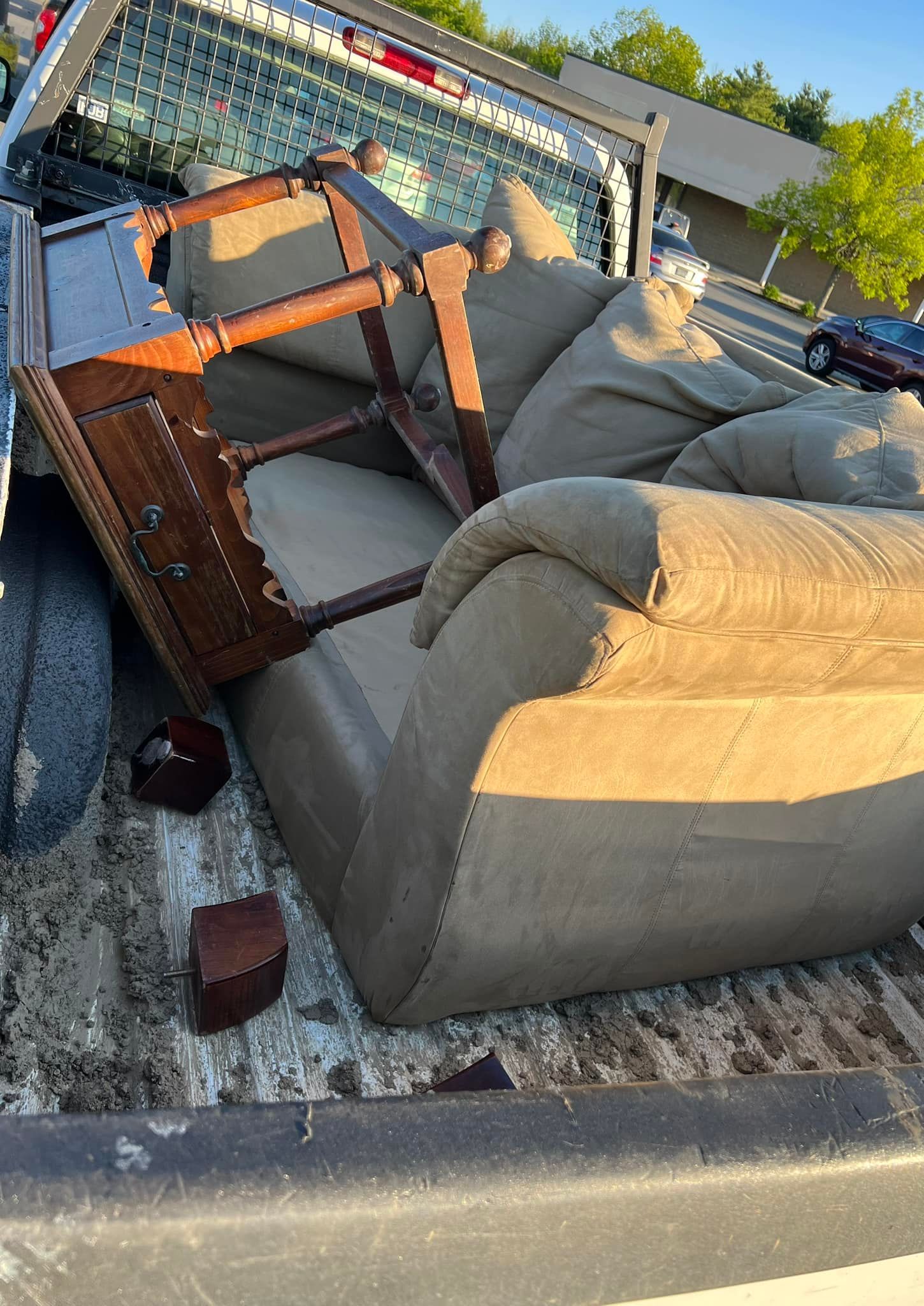Overturned couch and wooden table in a fenced outdoor patio area with gravel ground.