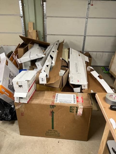 Cardboard boxes filled with white packaging scraps stacked in a garage beside a closed door