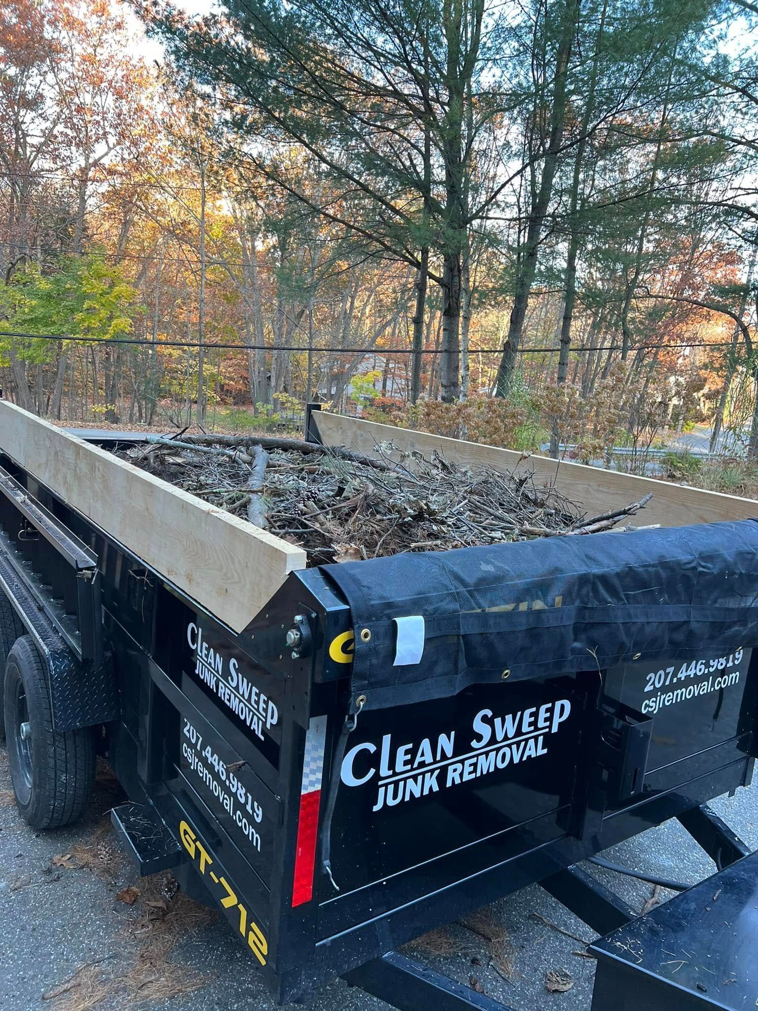 Black dump trailer filled with debris, labeled 