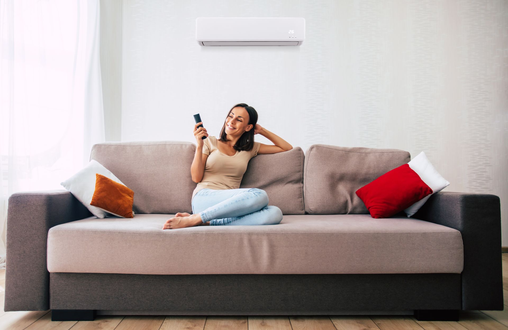 A woman is using the Mitsubishi Electric air conditioner while sitting on the couch and resting.
