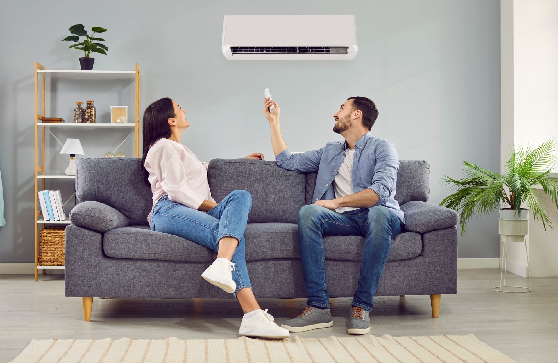 A couple is turning on the air conditioner and sitting on the sofa at home. A couple is turning on the air conditioner and sitting on the sofa at home.
