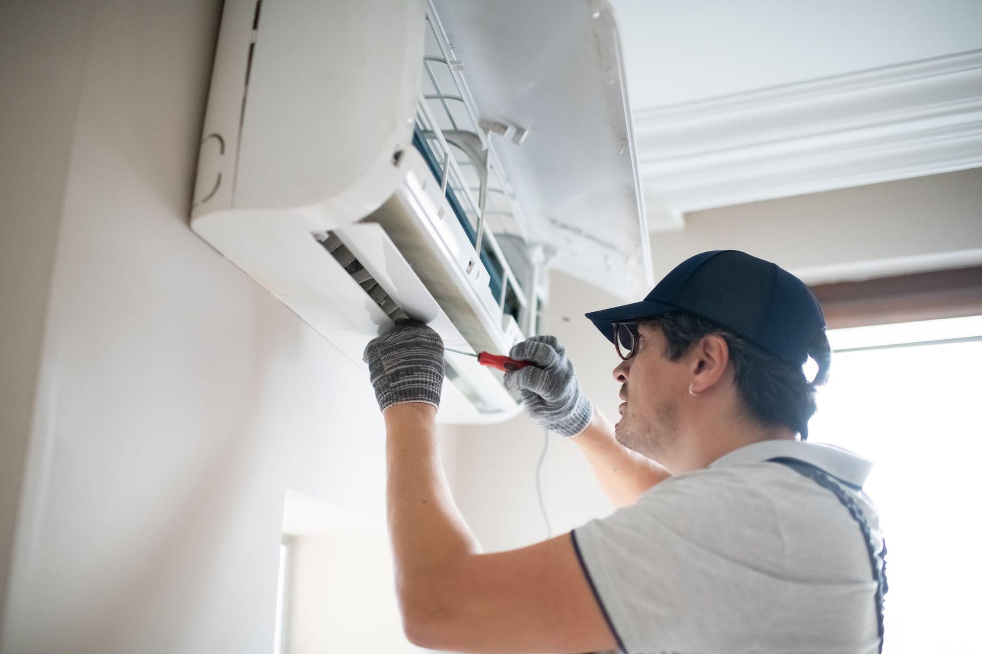 A technician repairing an air conditioner at a residence.