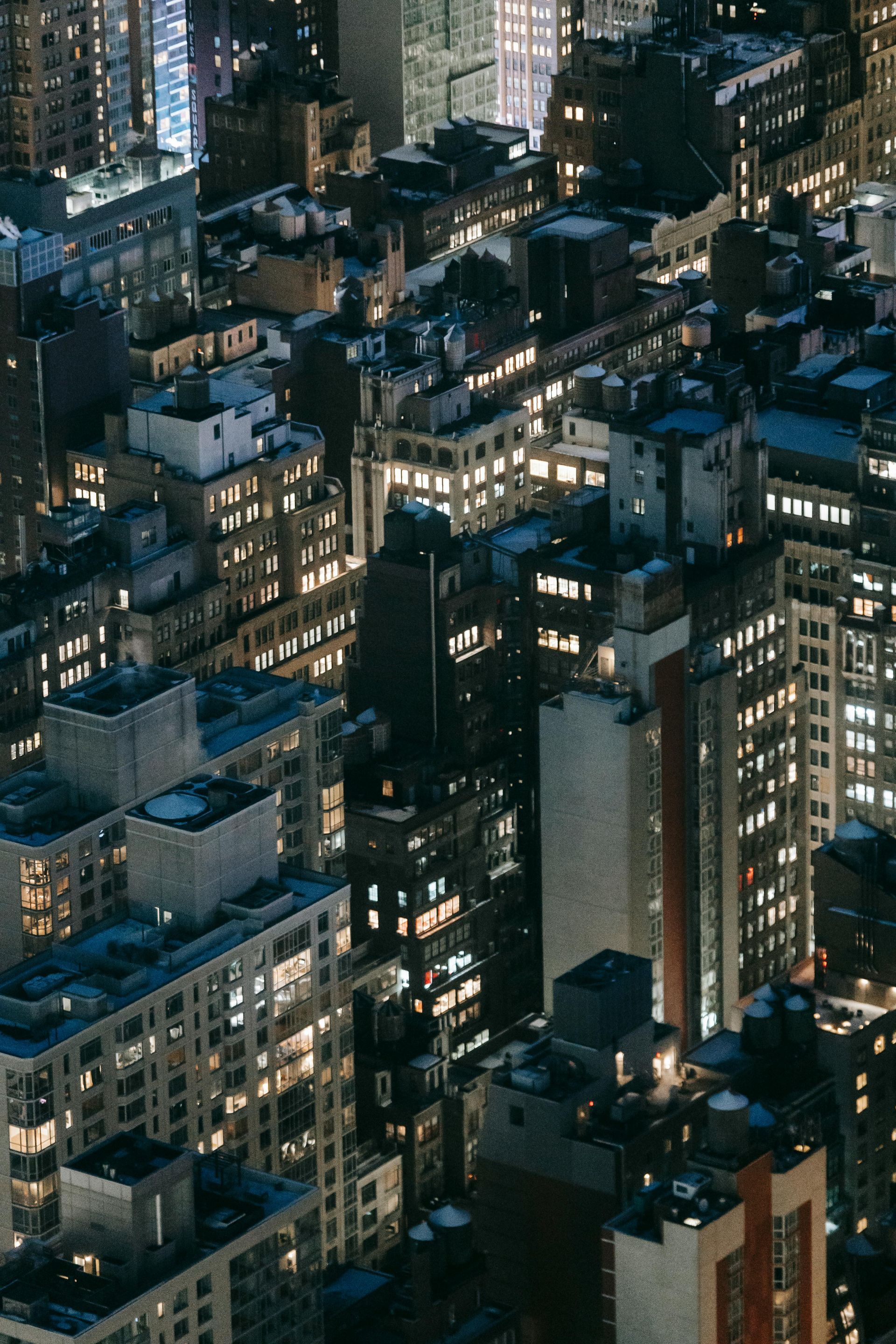Une vue aérienne d'une ville la nuit avec de nombreux bâtiments illuminés.