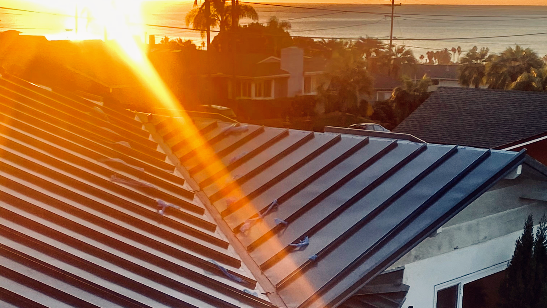 Sunset illuminates rooftops with palm trees in the background.
