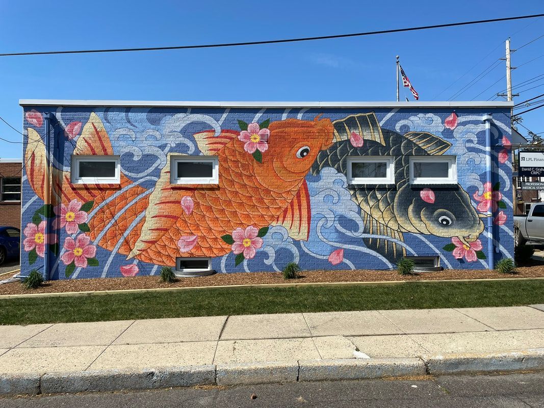 A mural on a building wall depicts two large koi fish swimming through blue stylized waves, accented with pink flowers.