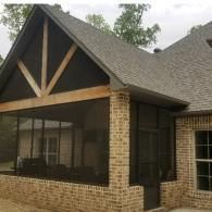 Brick house porch with dark screened windows and a steep gabled roof