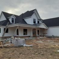 New white house under construction with unfinished porch and scattered building materials in front