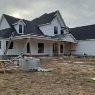 New house under construction with unfinished yard and white siding, viewed from the front