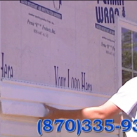 Person holding a large sheet near a building wall with blue text and a visible phone number