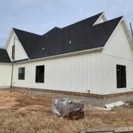 Partially built white house with black roof and unfinished yard