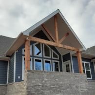 Modern house exterior with a covered porch, stone facade, and large triangular gable accents
