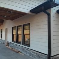 Side view of a modern house exterior with white siding, black-framed windows, and a covered porch