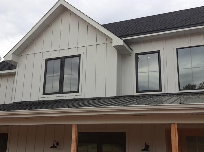 Front of a two-story gray house with black roof and covered porch