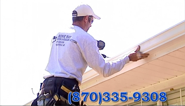 Worker installing gutter on a house roofline with phone number (870)335-9308