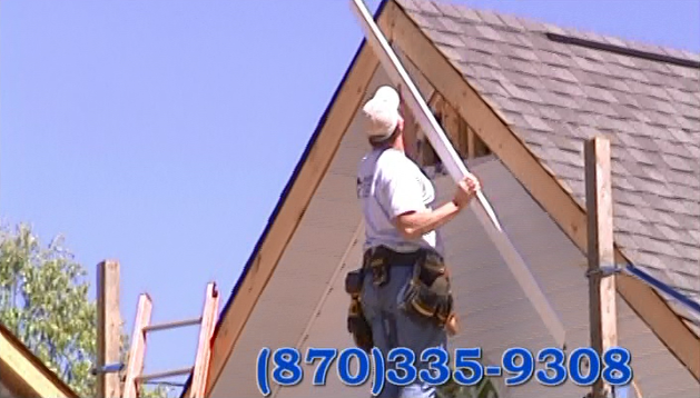Worker on a roof installing a wooden beam beside a house, with phone number 870-335-9308 displayed.