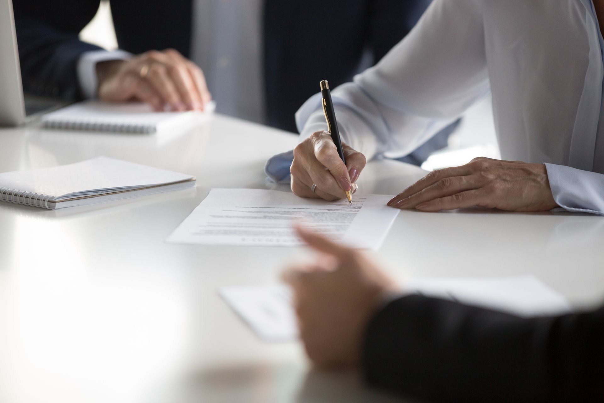 A man and a woman are sitting at a table signing a divorce agreement.
