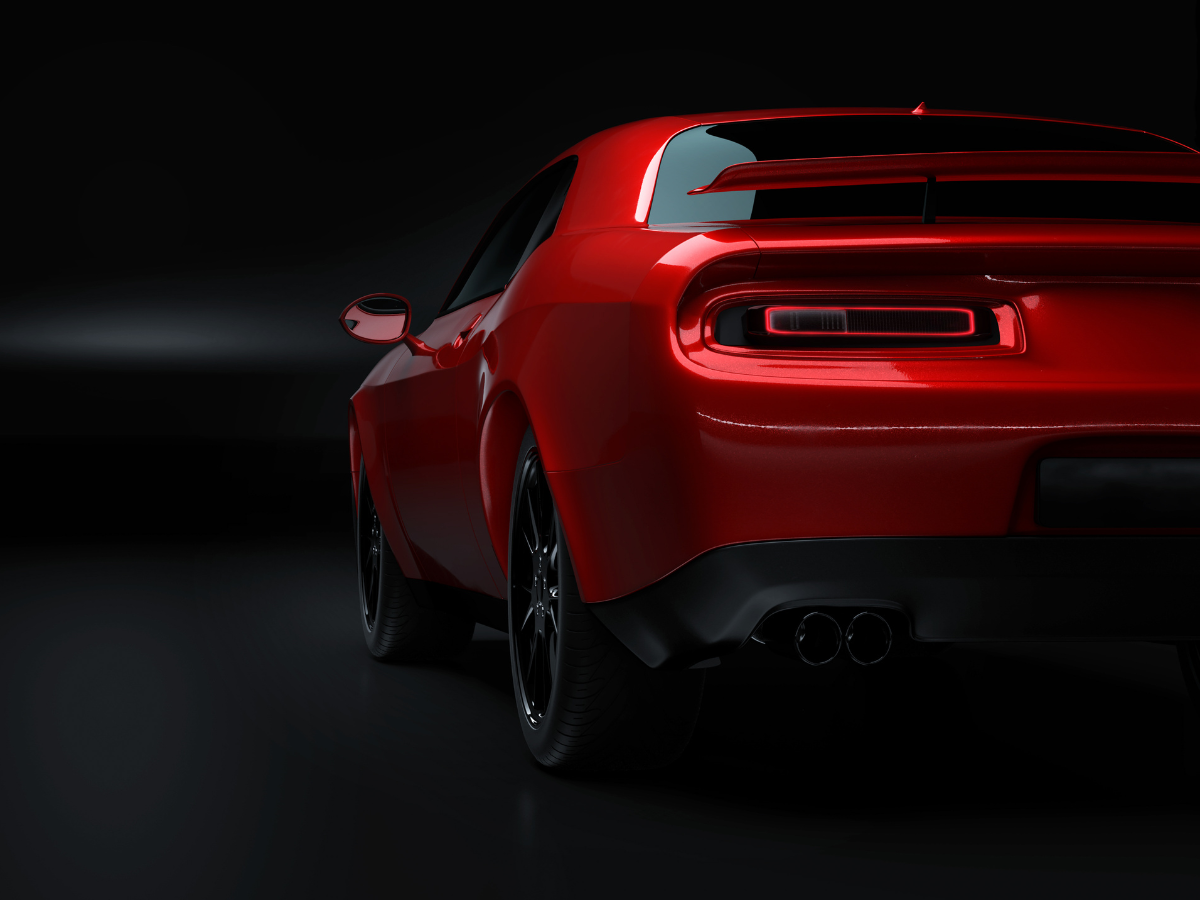Red sports car viewed from the rear on a dark background, glowing taillights and glossy finish