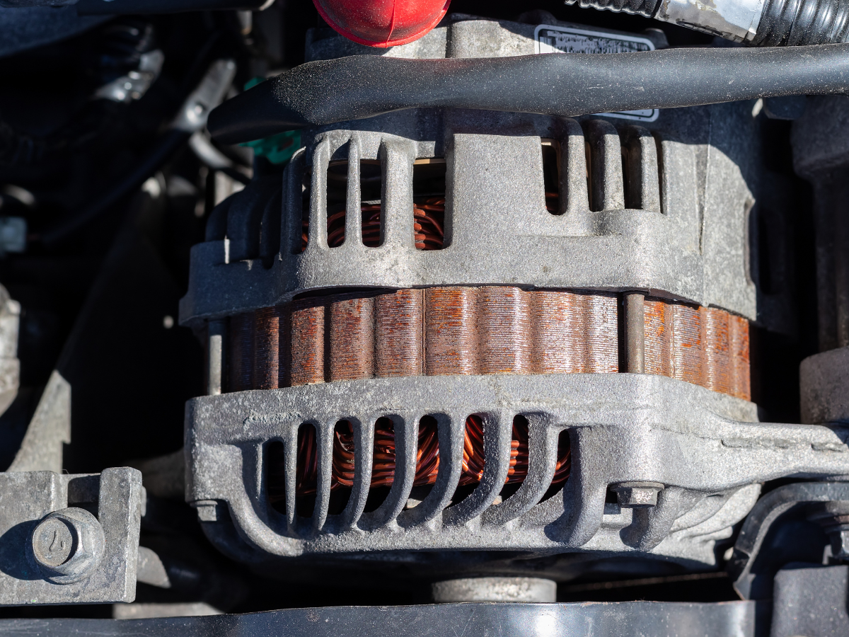 Close-up of a metal alternator with copper windings inside an engine compartment