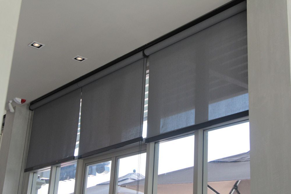 Four Grey Roller Blinds on Windows With a White Ceiling