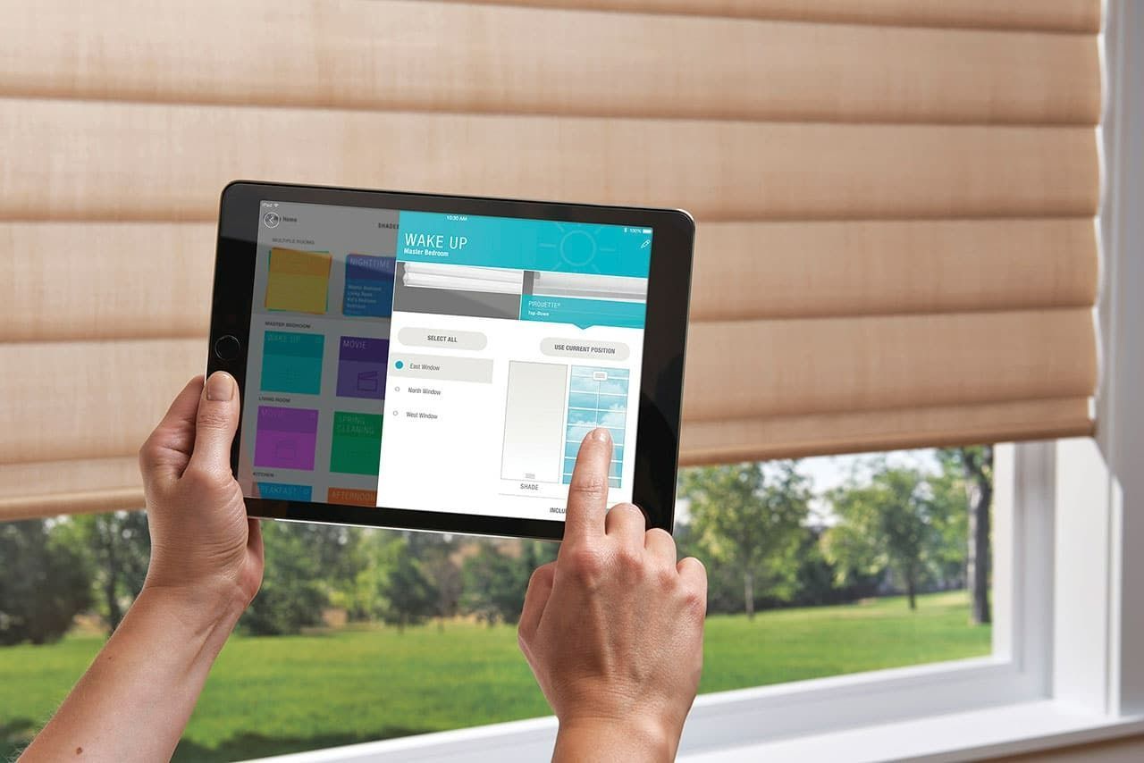 Person is holding a tablet in front of a window — Blinds in Bogangar, NSW