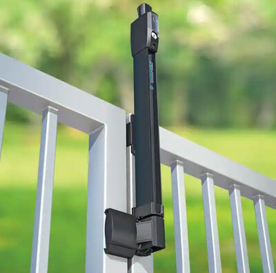 Black gate closer mounted on a metal gate; green background.