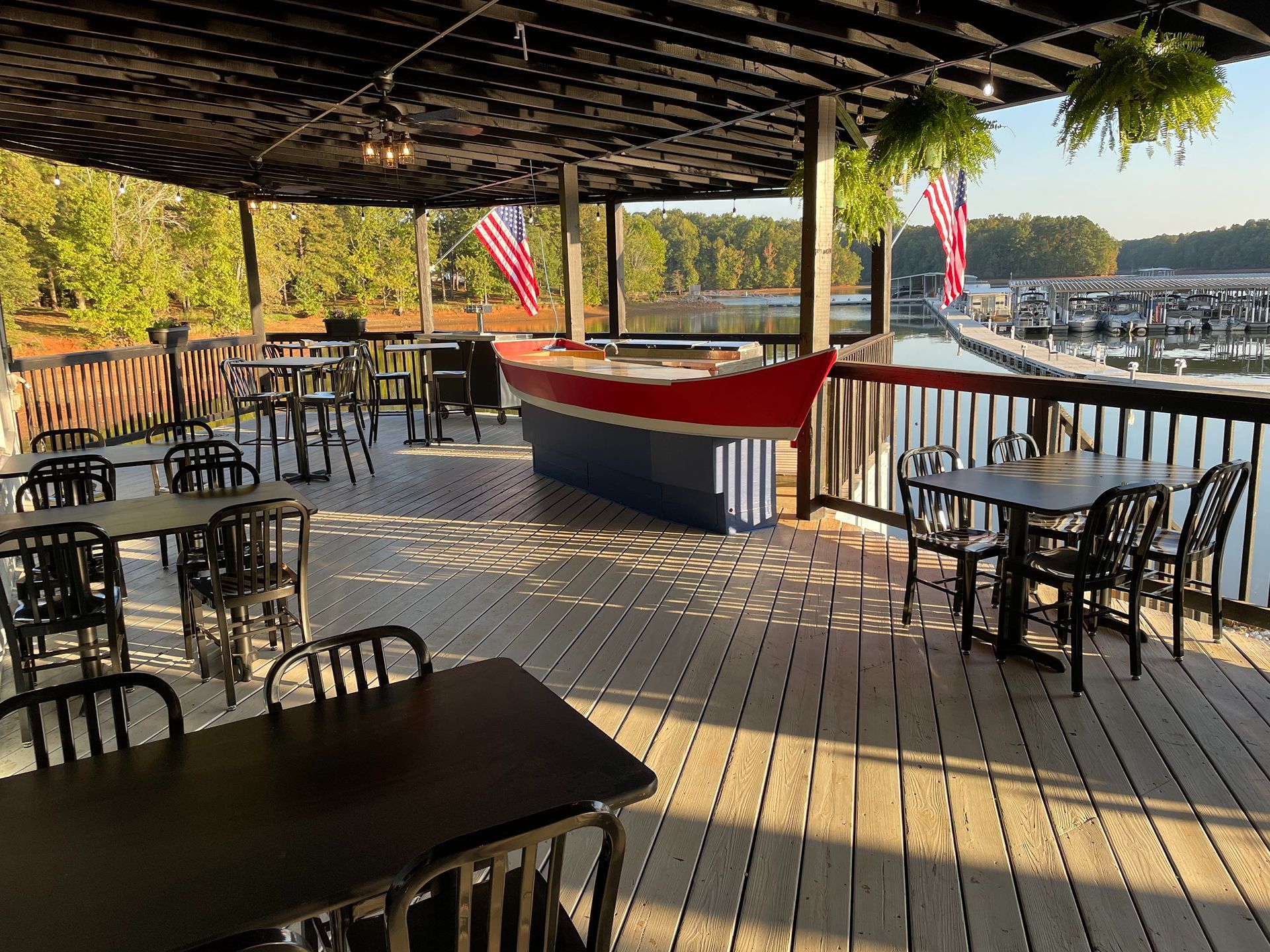 Outdoor patio overlooking a marina, featuring tables, chairs, and a decorative boat.