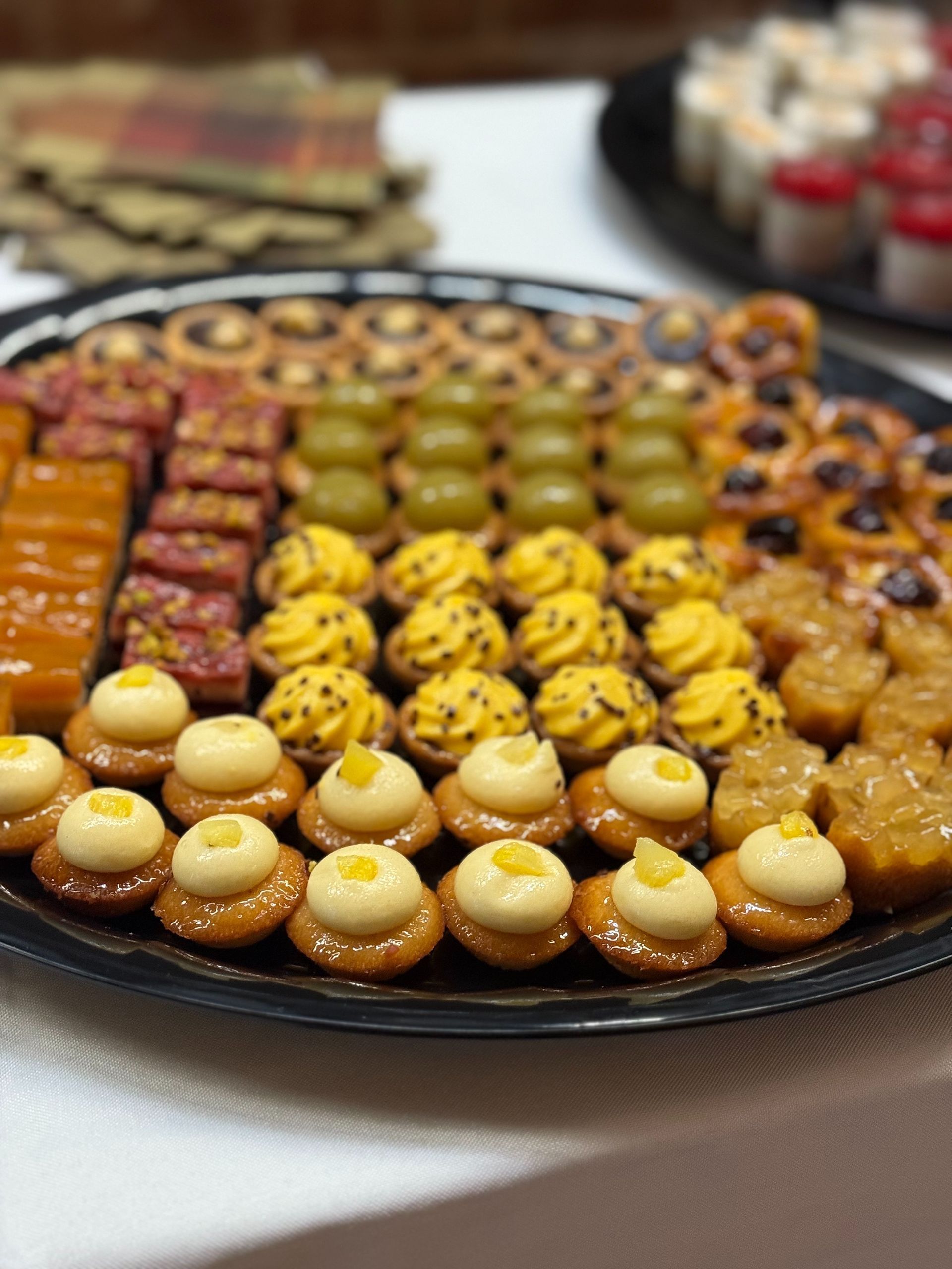 Tray of assorted colorful pastries: yellow, orange, and red treats arranged for serving.