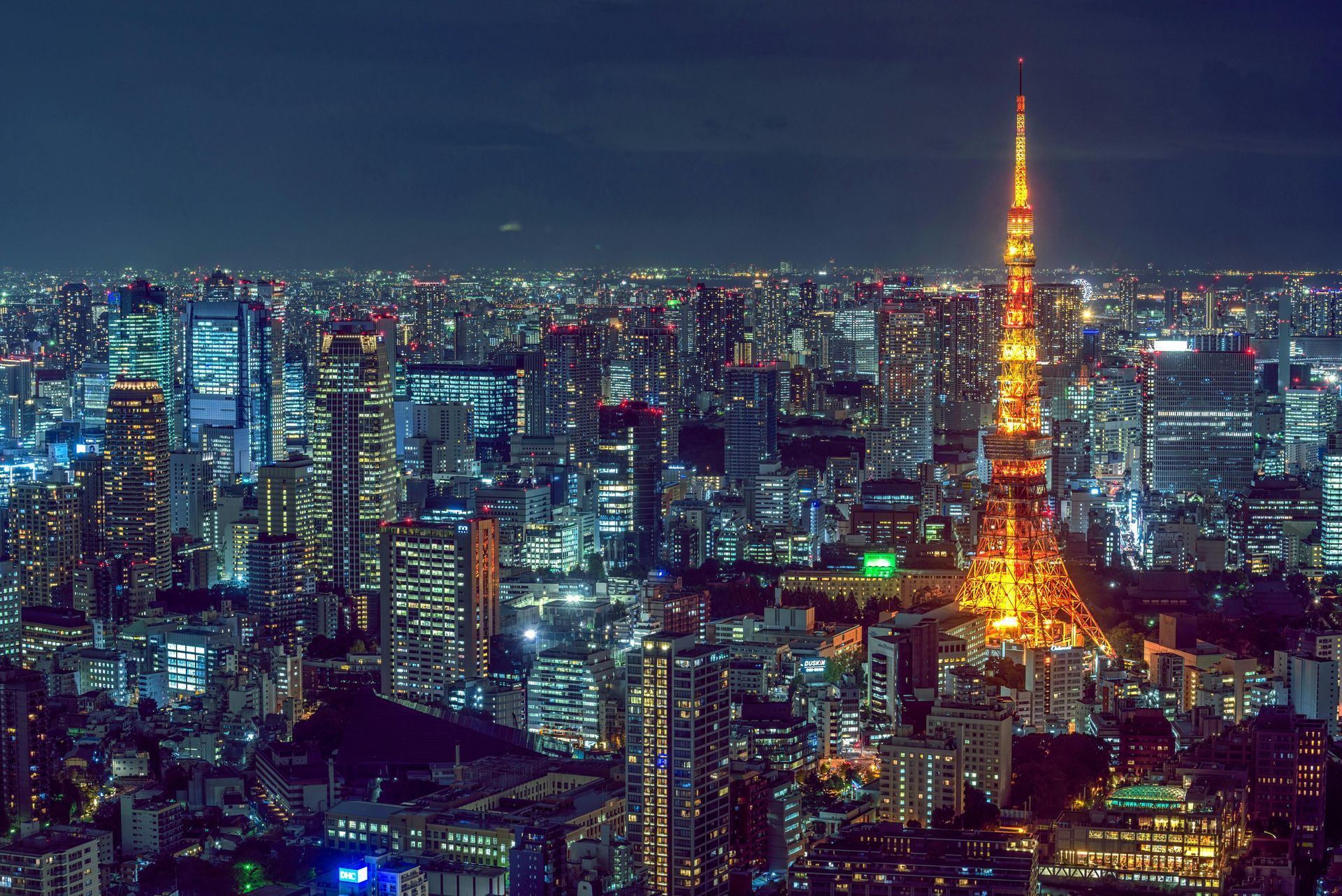 Tokyo skyline at night, with illuminated orange Tokyo Tower dominating the view among city lights.