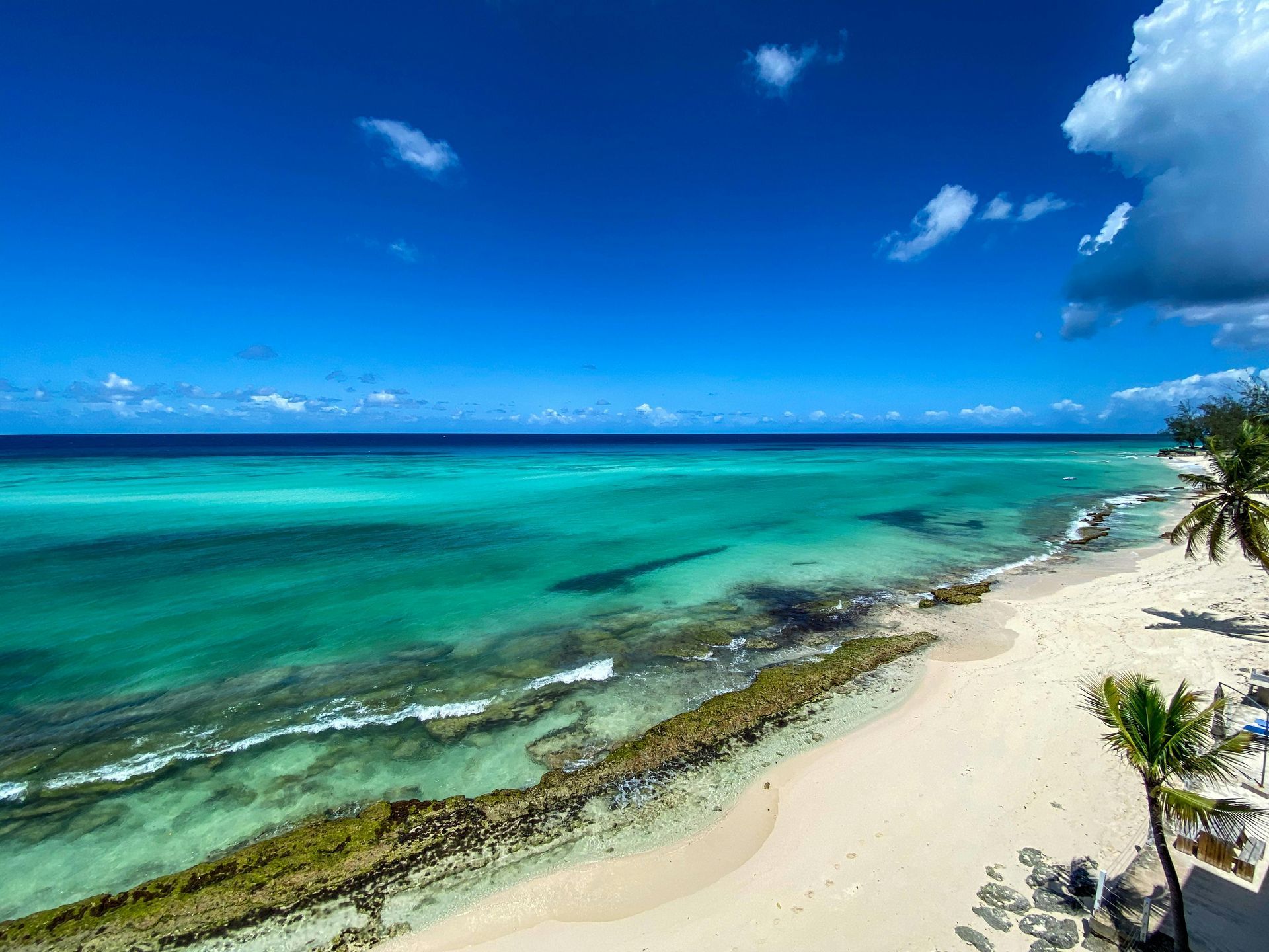 Bright turquoise ocean meets white sand beach under a brilliant blue sky.
