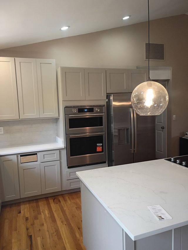 Modern kitchen with white cabinets, stainless steel appliances, and a large island under pendant lighting