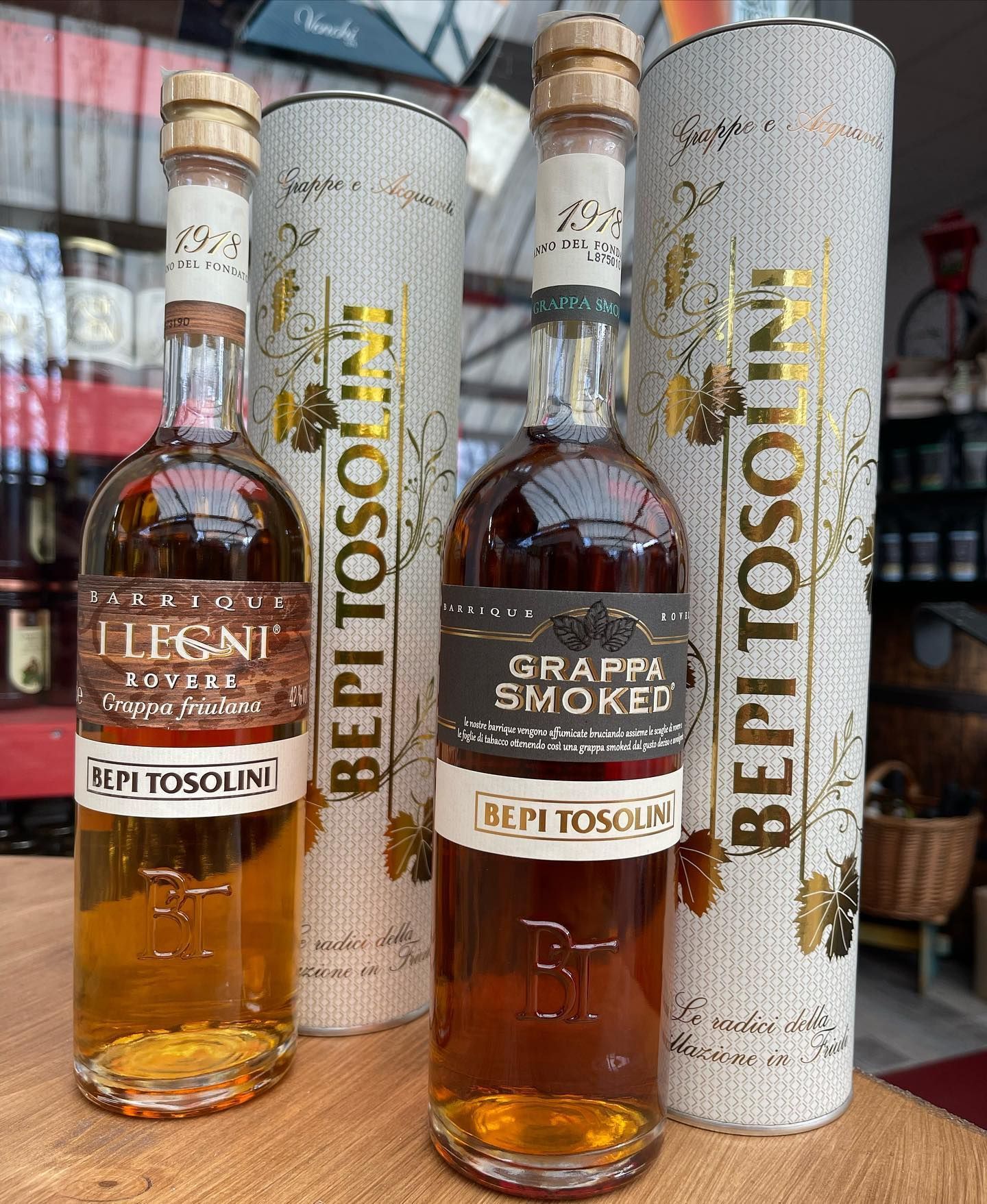 Tre bottiglie di grappa affumicata sono appoggiate su un tavolo di legno.