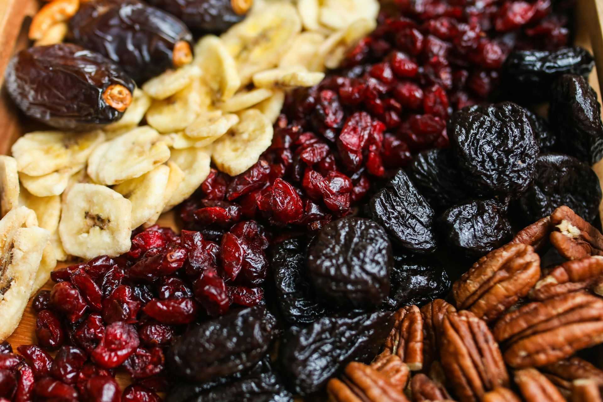 Una varietà di frutta secca e noci in una scatola di legno.