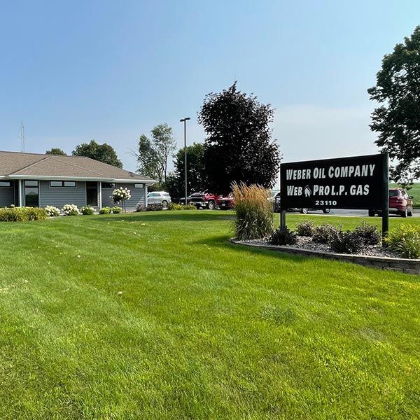 Wheeler Oil Company sign beside a grassy lawn and building under a clear blue sky
