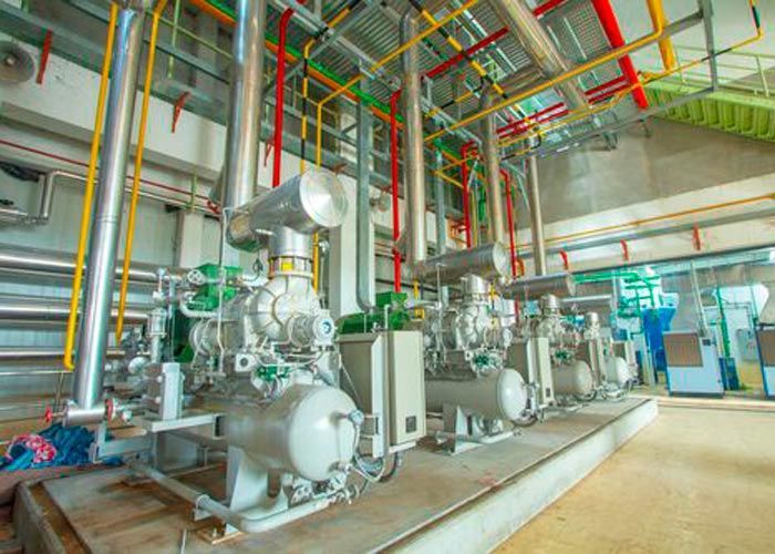 Industrial machinery and colorful pipes inside a large factory room