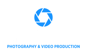 a man with a beard is holding a camera in front of waves .