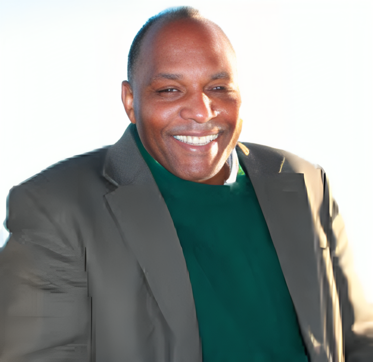 a man in a suit and green sweater is smiling for the camera .