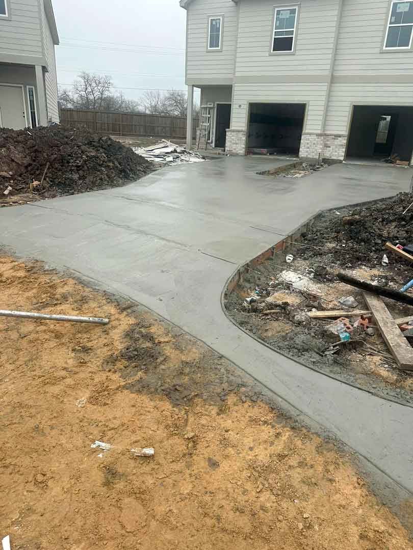 A concrete driveway is being built in front of a house.