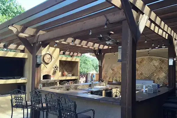 a large outdoor kitchen with a pergola and a ceiling fan .