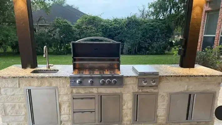 a large outdoor kitchen with a grill , sink , and cabinets .