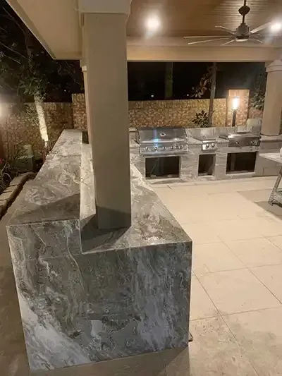 a large outdoor kitchen with a grill and a ceiling fan .