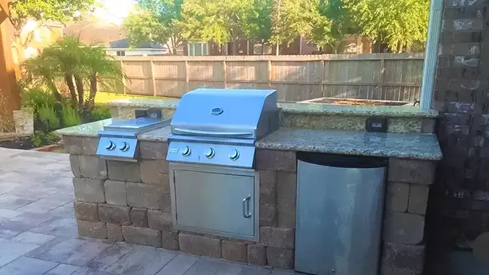 a stainless steel grill is built into a stone wall on a patio .