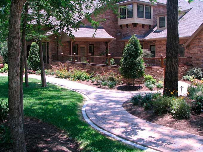 Beautiful red pavers path surrounded by grass and landscaping beds