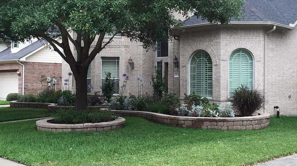 Landscaping stone beds with plants and tree for house appeal