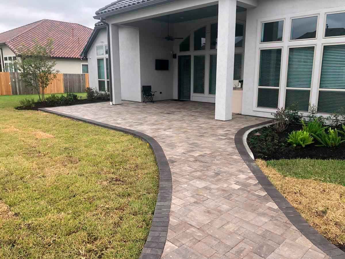 Diagonal light-pavers pathway ending in a covered patio