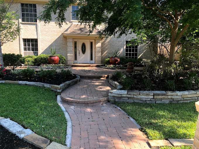 Red pavers walkway with step and landscaping for appeal