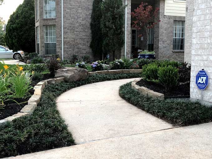 Concrete walkway bounded by elegant landscaping beds