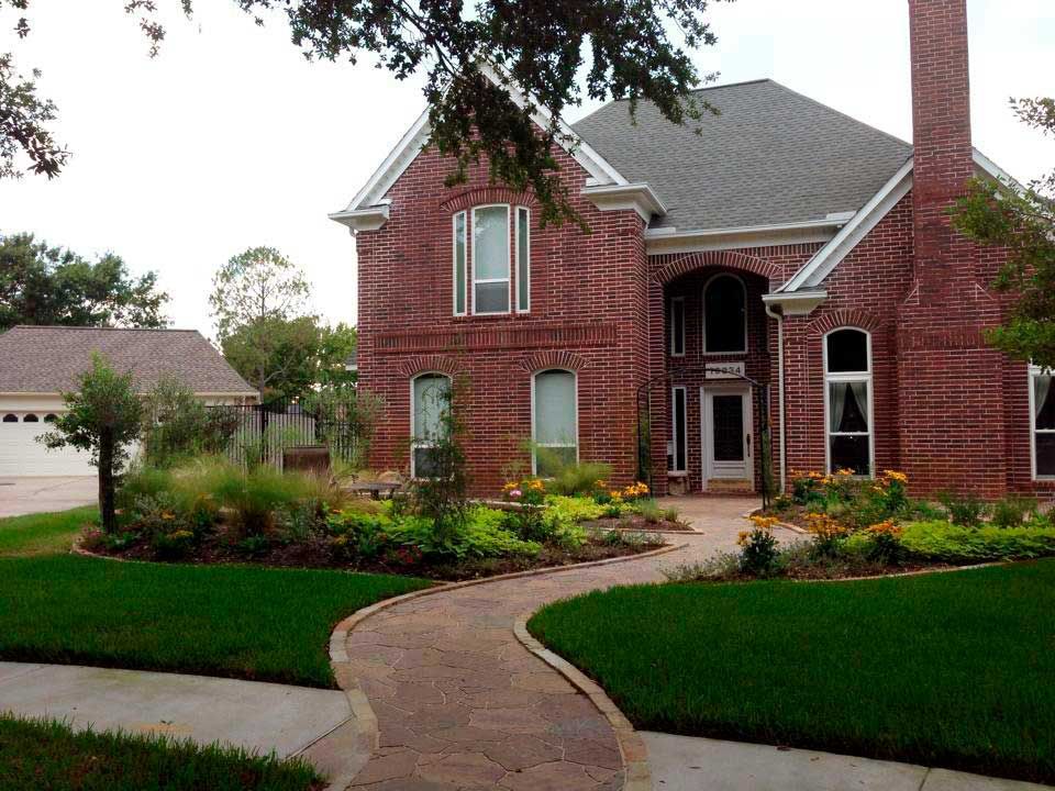 Pathway of red pavers with landscaping for appeal