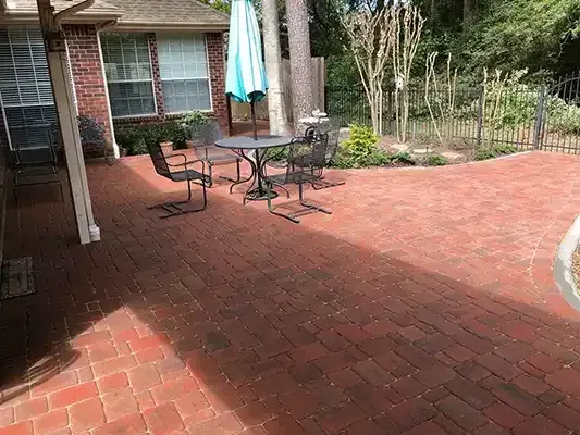 a brick patio with a table and chairs and an umbrella .